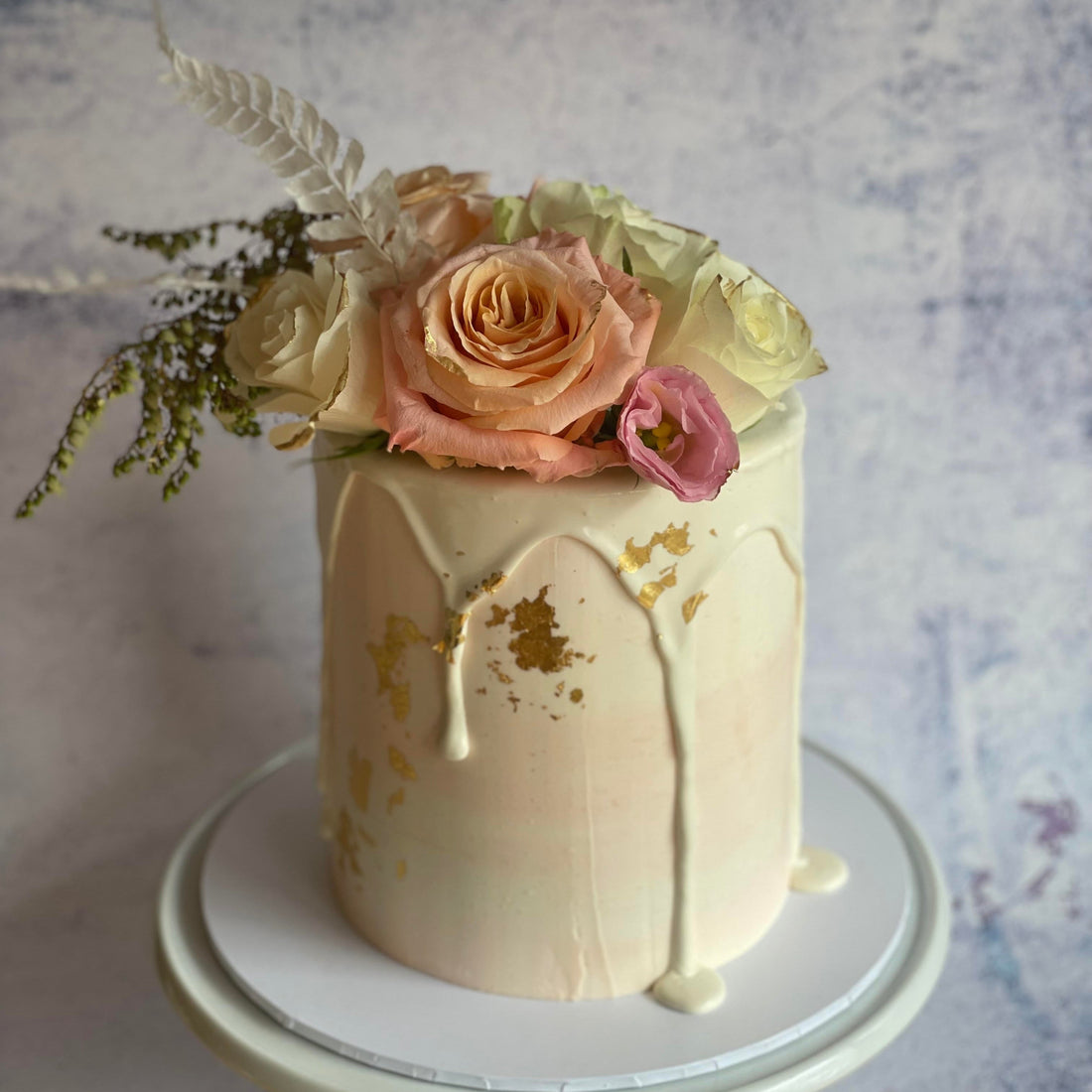 Handcrafted vegan celebration cake with fresh seasonal florals and drip styling