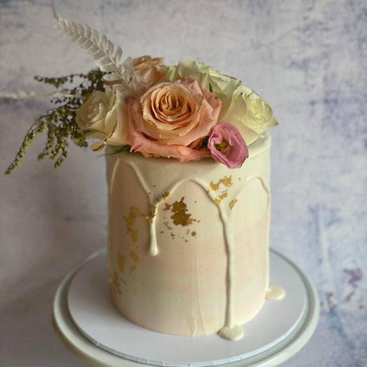 Handcrafted vegan celebration cake with fresh seasonal florals and drip styling